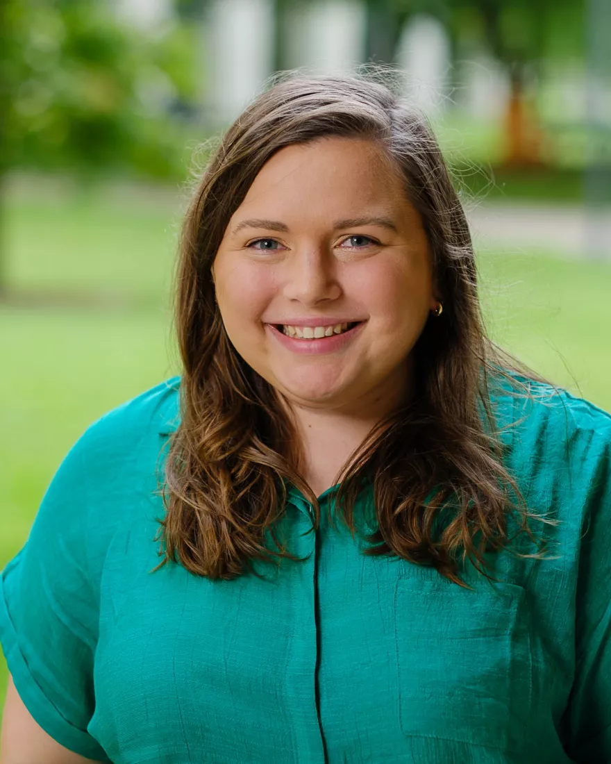 White woman with brown hair wearing a green shirt 