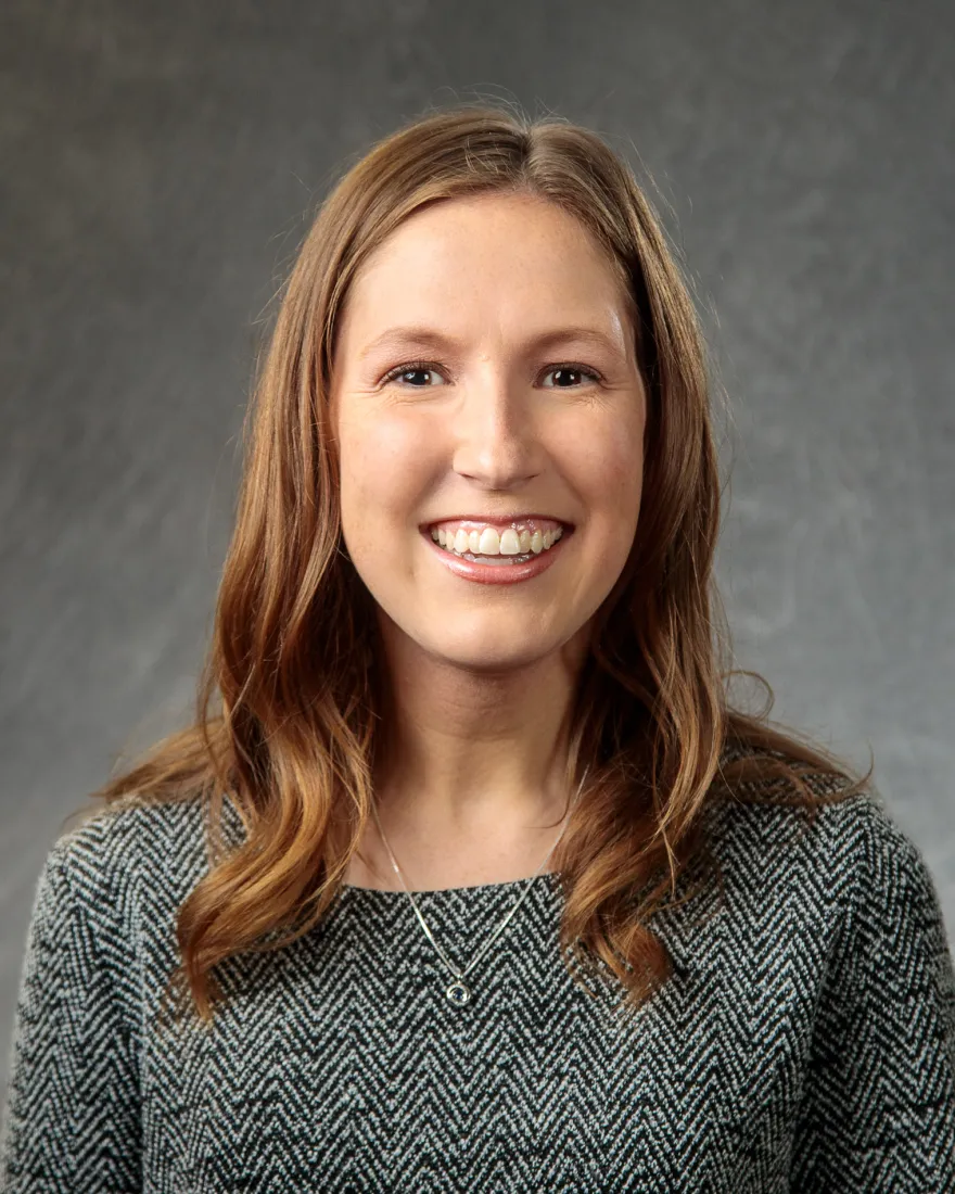Lady with brown hair and light skin, on a gray background.