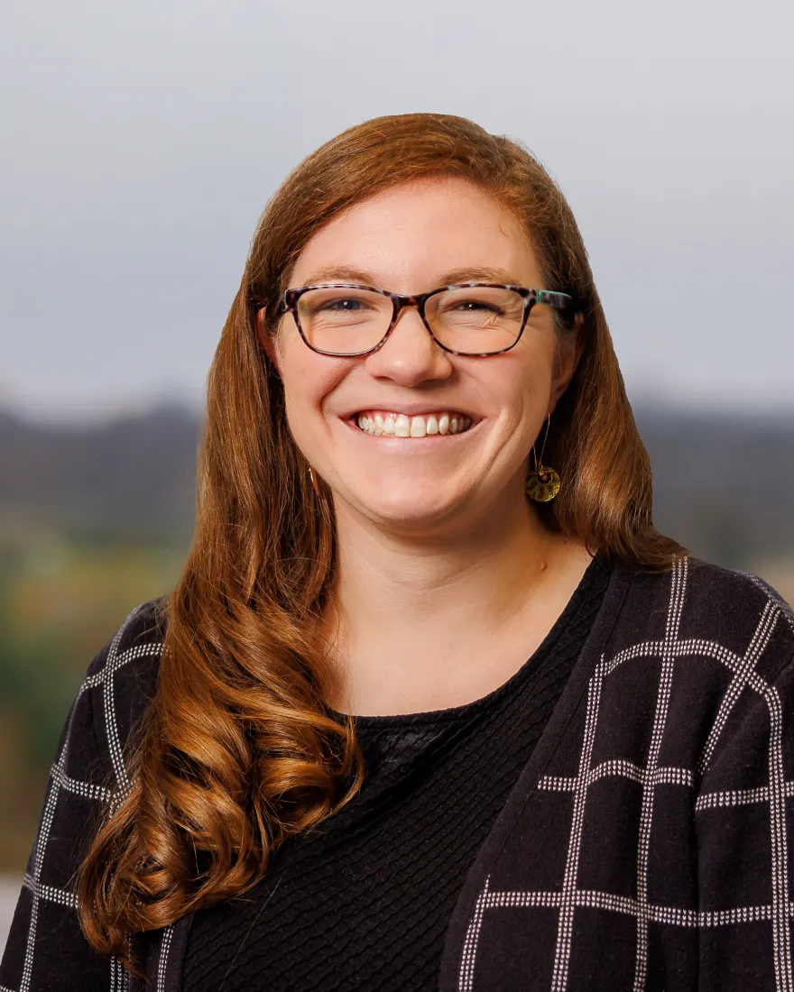 Image of a woman wearing glasses, a black dress, and a patterned cardigan.