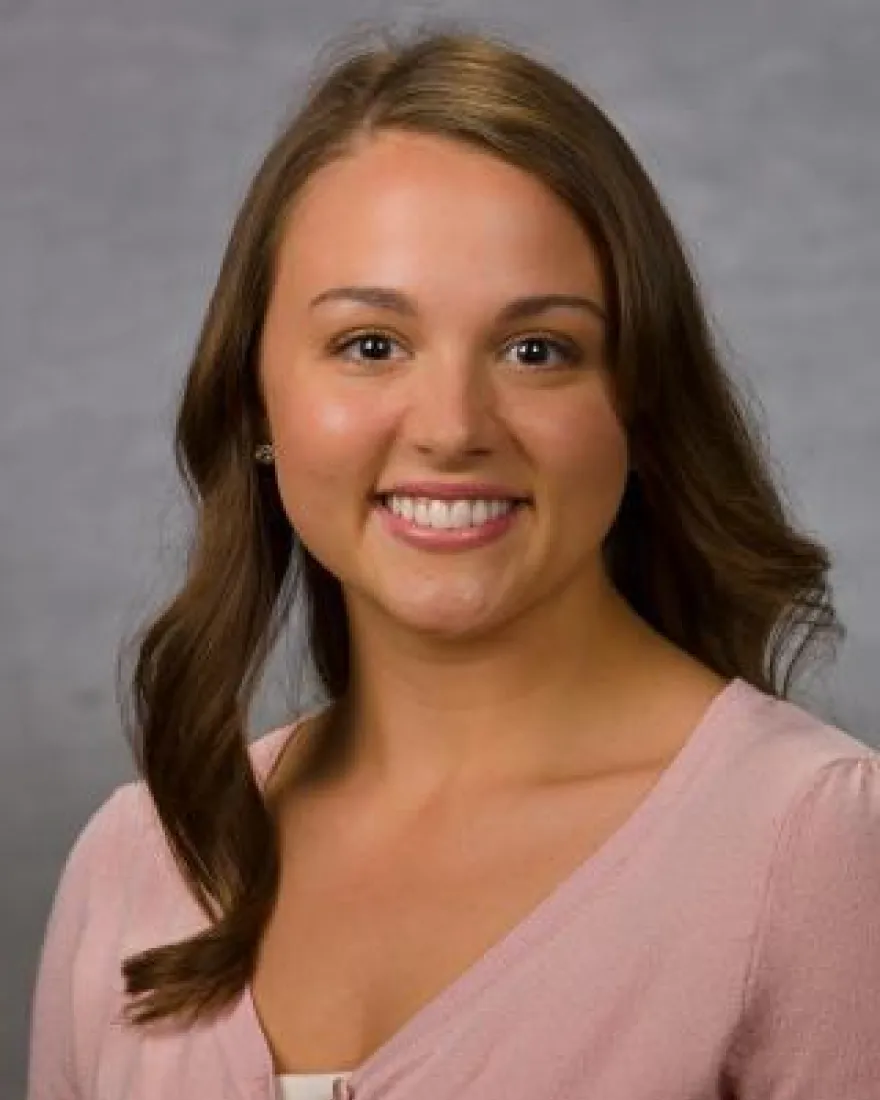 Professional headshot of woman in a pink top.